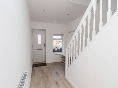 An entryway with a wooden front door a window a white staircase wooden floor and a radiator at Whitby View in Whitby