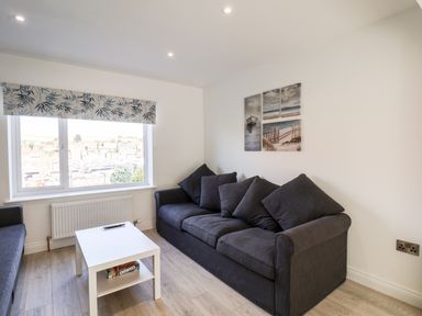 A living room with a dark sofa coffee table window and wall art at Whitby View in Whitby