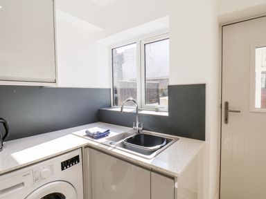 A kitchen sink with a faucet next to a window and a washing machine under the counter at Whitby View in Whitby