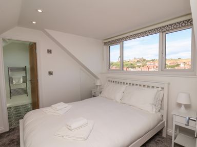 A bedroom with a double bed white bedding towels on bed and window showing town view at Whitby View in Whitby