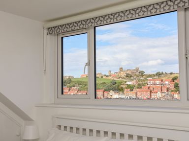 A window with a view of a hillside town with houses and historic buildings at Whitby View in Whitby