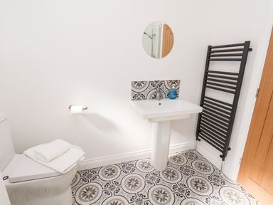 A bathroom with a toilet a sink a mirror and a black towel rack at Whitby View in Whitby