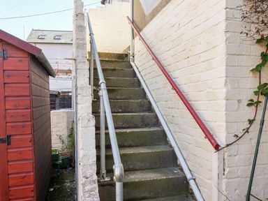 An outdoor concrete staircase with metal handrails next to a red wooden shed at Whitby View in Whitby