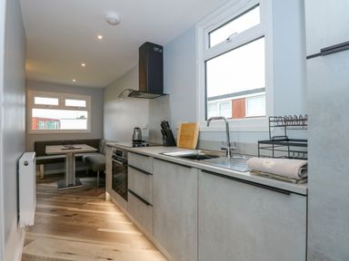 A kitchen with a countertop sink stove oven dining nook and windows at Number 9 in California Norfolk