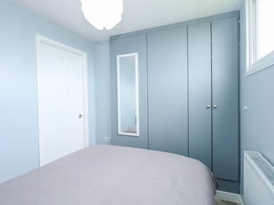 A bedroom with a bed a white door a wall mirror and built in wardrobes at Number 9 California Norfolk
