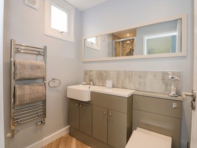 A bathroom with a sink cabinet and heated towel rack with two towels at Number 9 in California Norfolk