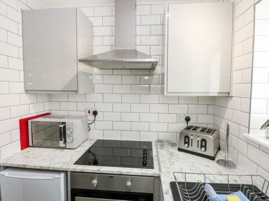 A kitchen with a microwave oven toaster stovetop and cabinets at 63 The Waterside Holiday Park in Corton