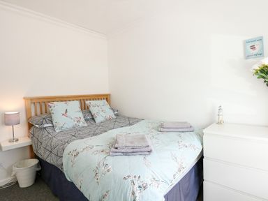A bedroom with a double bed nightstand lamp and white chest of drawers at 63 The Waterside Holiday Park in Corton