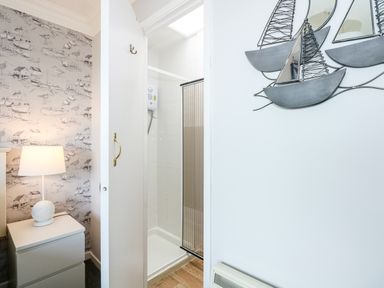 A bedroom corner with a nightstand and lamp next to an open door leading to a shower at 63 The Waterside Holiday Park in Corton