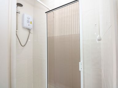 A shower area with a showerhead water heater and folding shower door at 63 The Waterside Holiday Park in Corton