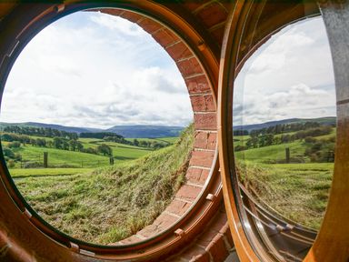 A round window with brick frame overlooking green fields and hills with trees at Badgers View in Rhayader