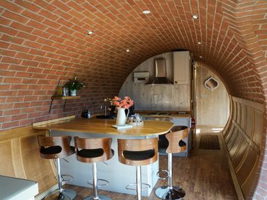 A kitchen with a curved brick ceiling wooden island with four bar stools and a flower vase at Hares View in Rhayader