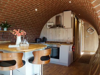 A kitchen with brick arched ceiling wooden countertop and stools at Hares View in Rhayader