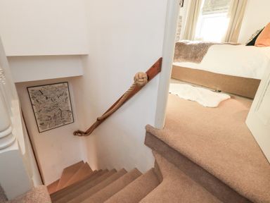 A staircase with rope railing and wall art at Gosling Cottage in Kendal