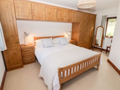 A bedroom with a wooden bed and built-in wooden wardrobes at Fountain Folly in Moylgrove near St Dogmaels