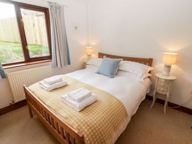 A bedroom with a double bed and bedside tables with lamps at Fountain Folly in Moylgrove near St Dogmaels