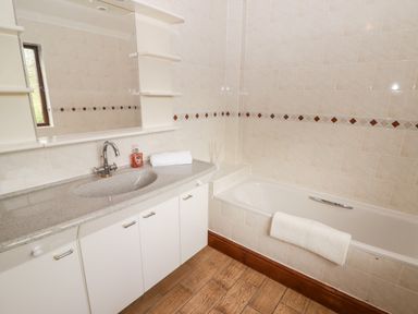 A bathroom with a sink countertop cabinet bathtub and a mirror at Fountain Folly in Moylgrove near St Dogmaels