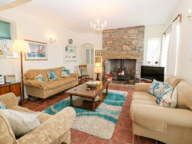 A living room with three sofas a wooden coffee table a stone fireplace and a television at Gorphwysfa in Llanddona near Beaumaris