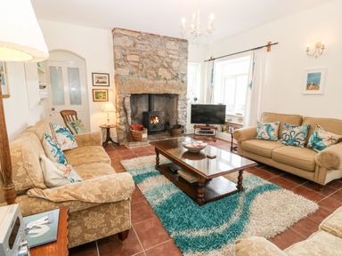 A living room with two sofas a stone fireplace a wooden coffee table and a television at Gorphwysfa in Llanddona near Beaumaris