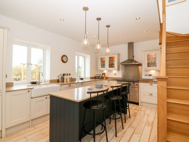 A kitchen with an island counter and three black stools at Gorphwysfa in Llanddona near Beaumaris