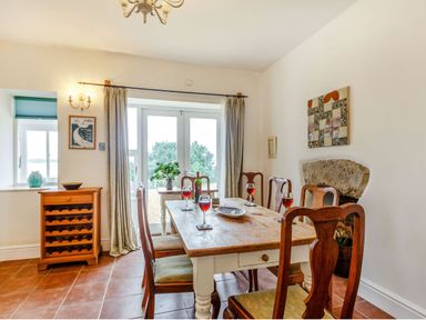 A dining room with a wooden table and chairs glasses of wine and a sideboard at Gorphwysfa in Llanddona near Beaumaris