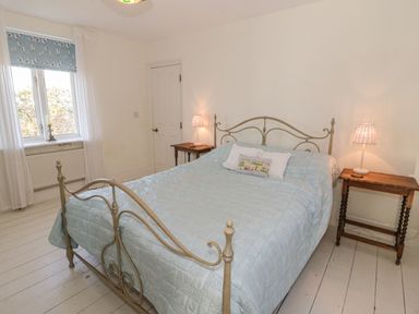 A bedroom with a metal bed frame side tables with lamps a window and a door at Gorphwysfa in Llanddona near Beaumaris