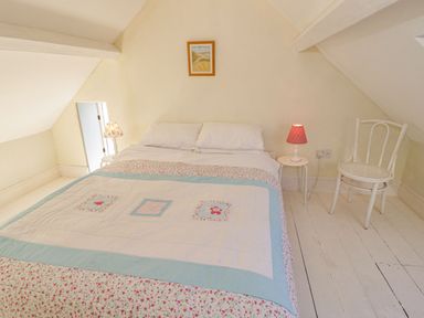 A bedroom with a double bed a chair two bedside tables with lamps and a picture on the wall at Gorphwysfa in Llanddona near Beaumaris