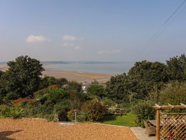 A garden with outdoor seating and a view of a beach and water at Gorphwysfa in Llanddona near Beaumaris