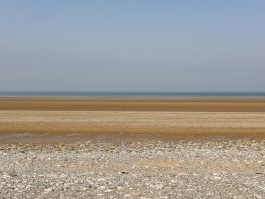 A beach with rocky foreground sandy middle ground and ocean in the background at Gorphwysfa in Llanddona near Beaumaris