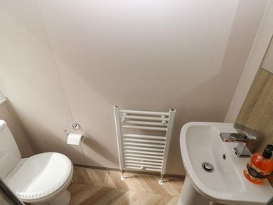 A bathroom with a toilet a white radiator a sink and a soap dispenser at Sandy Bay Retreat in Hasguard Cross near Broad Haven