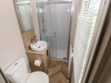 A small bathroom with a toilet sink shower and window blinds at Sandy Bay Retreat in Hasguard Cross near Broad Haven