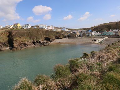 A coastal village with houses on cliffs and a calm bay with beach at Sandy Bay Retreat in Hasguard Cross near Broad Haven