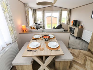 A dining area with table set for four and a living room with sofa and tv in a compact space at Sandy Bay Retreat Hasguard Cross near Broad Haven