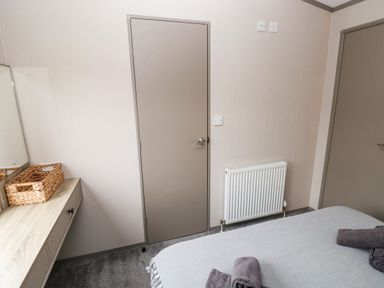 A bedroom with a bed towels a heater a desk with a basket and two closed doors at Sandy Bay Retreat Hasguard Cross near Broad Haven