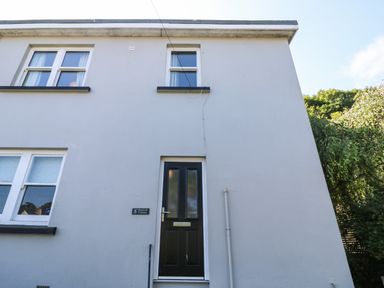 The exterior of a white building with a door and three windows at 8 Rosewall Cottages in St Ives