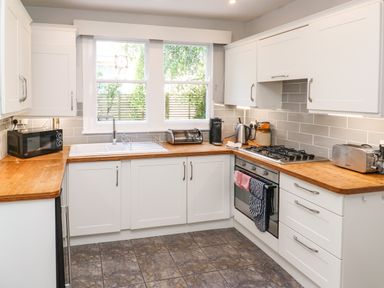 A kitchen with white cabinets wooden countertops a sink oven stovetop microwave and toaster at 8 Rosewall Cottages St Ives