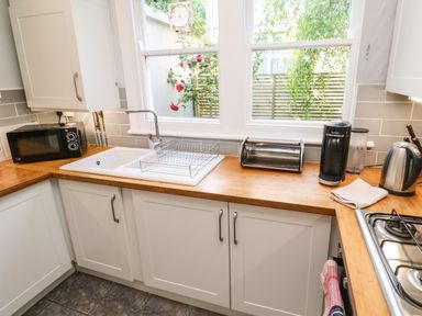 A kitchen with a sink microwave toaster coffee machine and kettle on wooden countertops at 8 Rosewall Cottages in St Ives