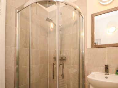 A bathroom with a glass shower enclosure next to a sink with a mirror at 8 Rosewall Cottages in St Ives
