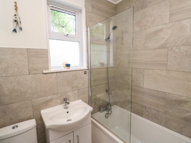 A bathroom with a bathtub shower and sink under a window at 8 Rosewall Cottages in St Ives