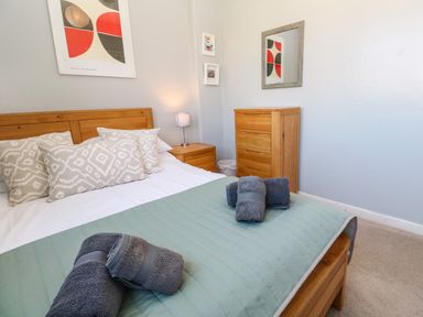 A bedroom with a wooden bed and dresser with towels on the bed at 8 Rosewall Cottages in St Ives