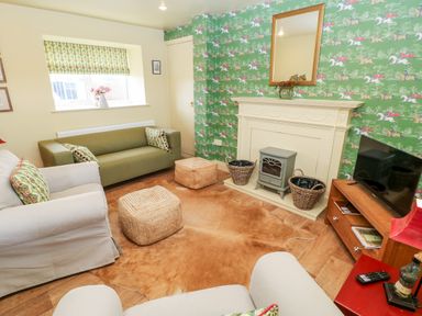 A living room with green wallpaper a fireplace and a television at The Granary in Longwitton near Morpeth