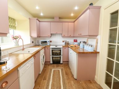 A kitchen with pink cabinets wooden countertops an oven and various appliances at The Granary in Longwitton near Morpeth