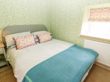 A bedroom with a double bed blue blanket and patterned pillows at The Granary in Longwitton near Morpeth