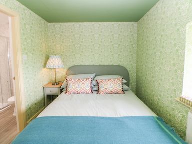 A bedroom with a bed pillows bedside table lamp and bathroom visible through door at The Granary in Longwitton near Morpeth