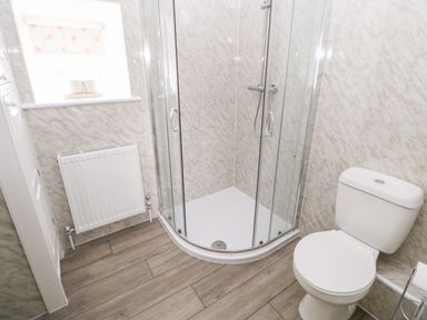 A bathroom with a shower enclosure toilet radiator and a small window at The Granary in Longwitton near Morpeth