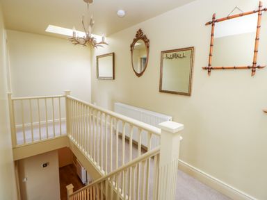A hallway with a staircase railing and four wall mirrors at The Granary in Longwitton near Morpeth