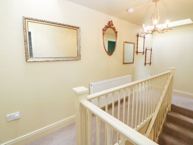 A staircase landing with mirrors on the wall a radiator and a chandelier at The Granary in Longwitton near Morpeth