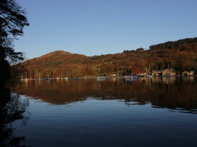 A lake with boats moored and hills in the background at The Lodge in Newby Bridge