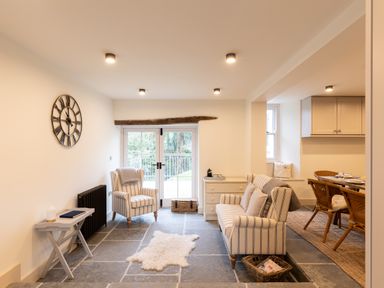 A living room with striped armchairs and a sofa a small table and a clock on the wall at The Lodge in Newby Bridge
