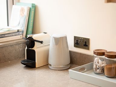 A kitchen countertop with a white nespresso machine a white kettle two glass jars with wooden lids and cookbooks at The Lodge in Newby Bridge